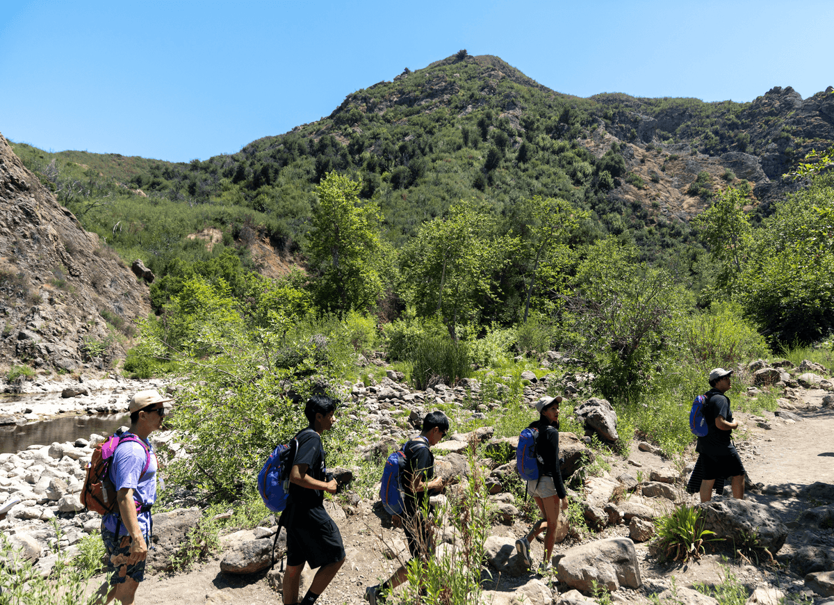 Group of hikers on a rocky trail in Malibu Creek State Park with mountains in the background
